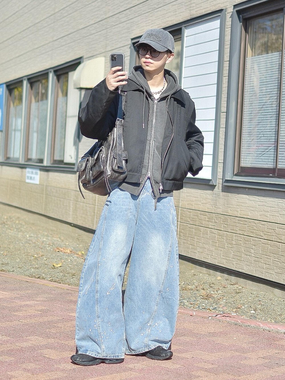 ブルー系のデニムパンツ、ブラック系のブルゾン、グレー系のパーカーを着用したメンズの秋コーディネートの2枚目の写真