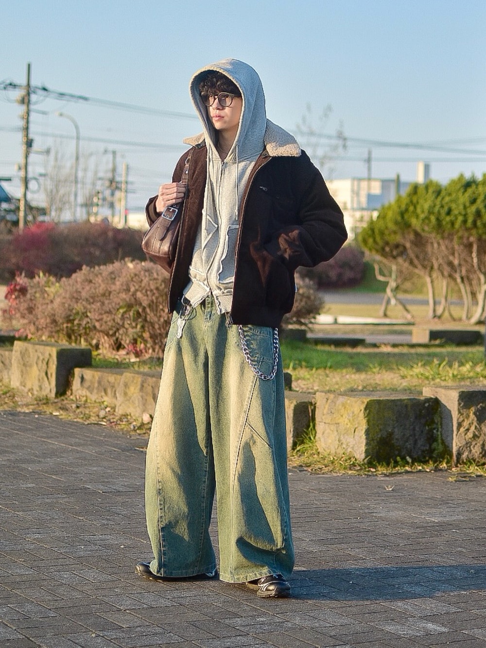 ブラウン系のブルゾン、ブルー系のデニムパンツ、グレー系のパーカーを着用したメンズの秋コーディネートの4枚目の写真