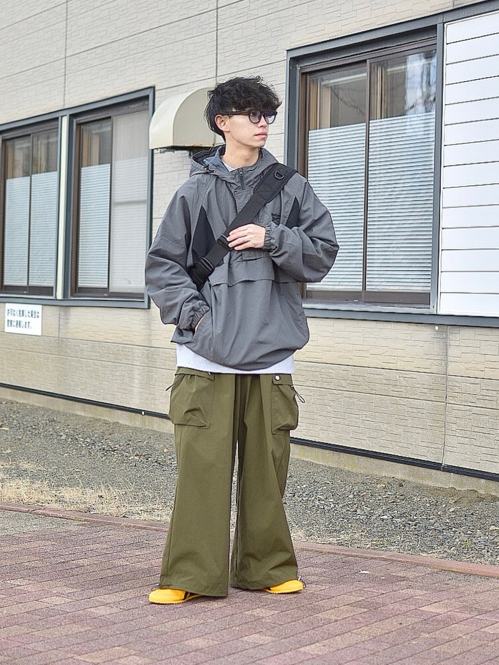 グレー系のナイロンジャケット、グレー系のスウェット、グリーン系のカーゴパンツを着用したメンズの秋コーディネートの2枚目の写真