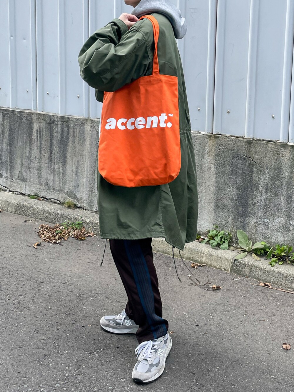 ブラウン系のパンツ、オレンジ系のトートバッグを着用したメンズの秋コーディネートの2枚目の写真