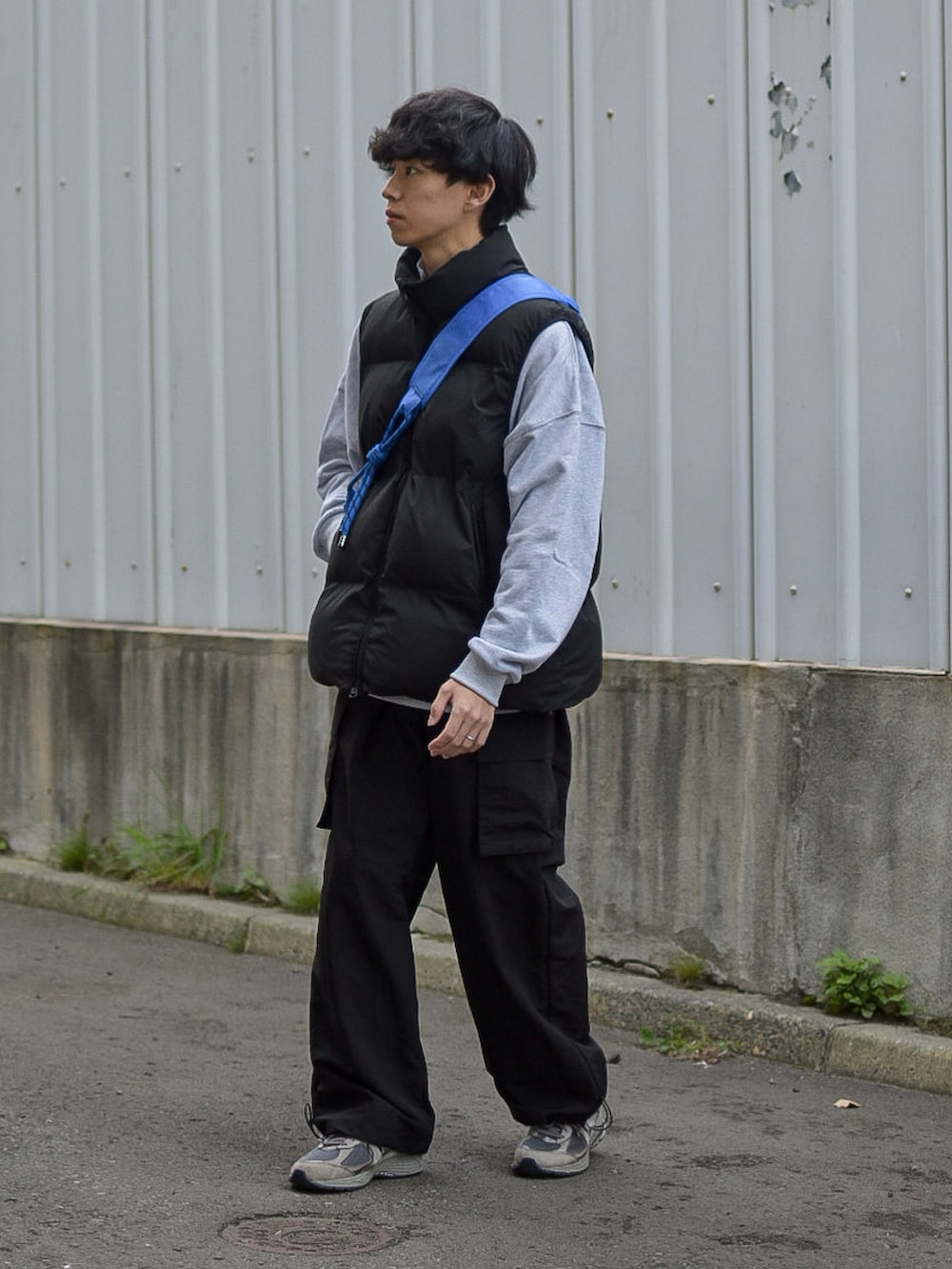 ブラック系のダウンベスト、グレー系のスウェット、ブルー系のショルダーバッグを着用したメンズの秋コーディネートの2枚目の写真