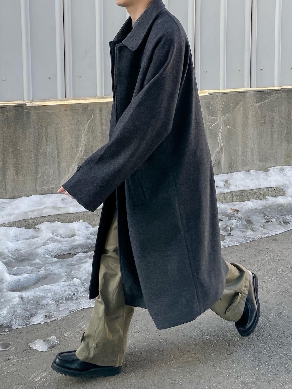 グレー系のニット/セーター、グレー系のステンカラーコートを着用したメンズの冬コーディネートの3枚目の写真