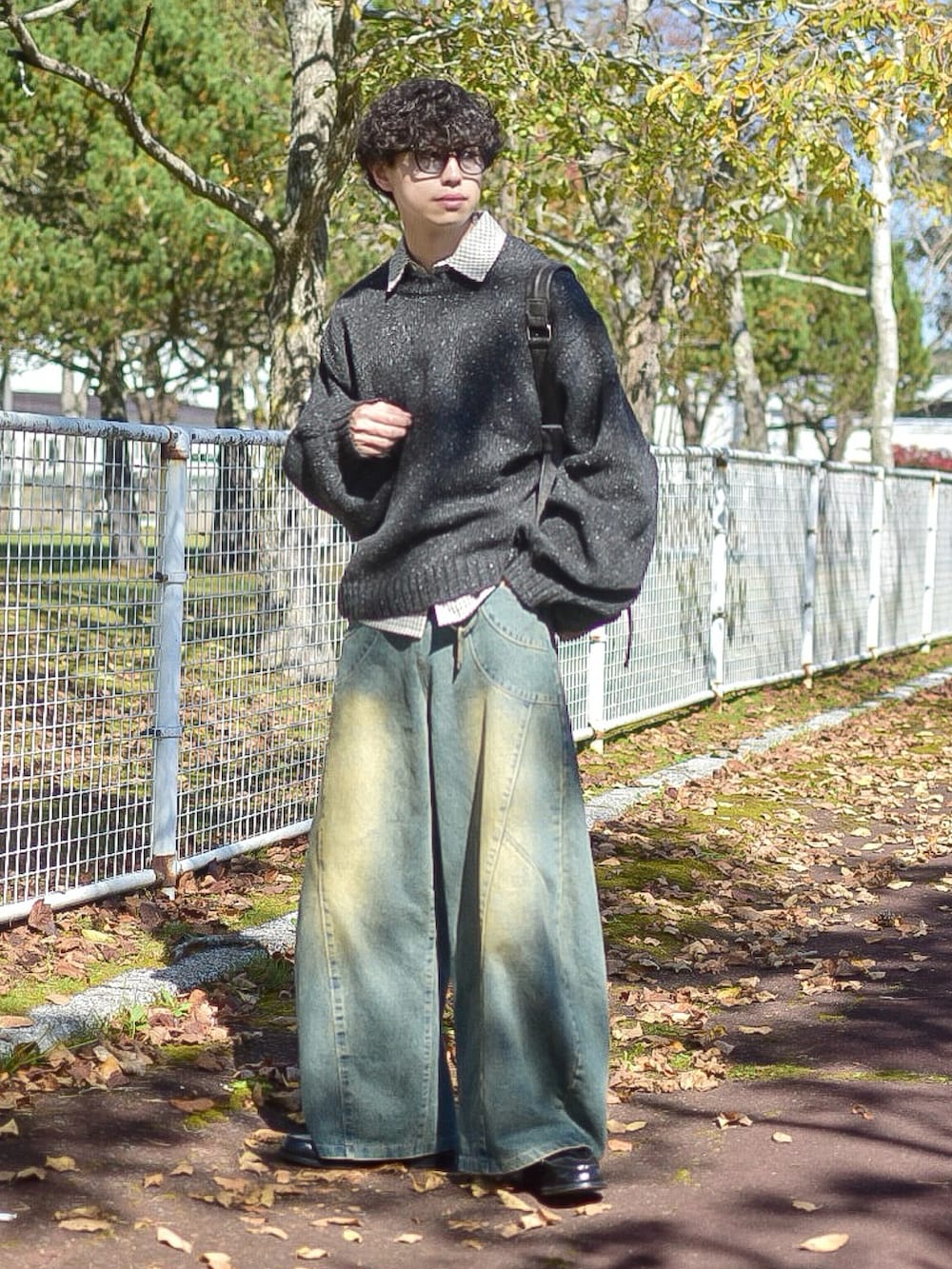 ブラック系のニット/セーター、ホワイト系のシャツ/ブラウス、ブルー系のデニムパンツを着用したメンズの秋コーディネートの4枚目の写真