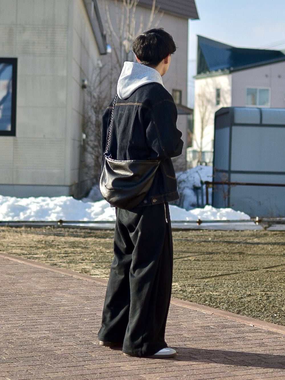 ブルー系のデニムジャケット、グレー系のパーカー、ブラック系のスウェットパンツを着用したメンズの春コーディネートの3枚目の写真