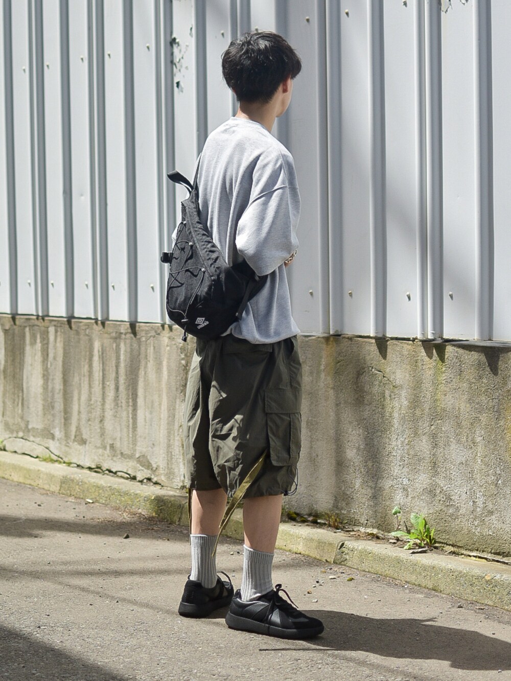 グレー系のTシャツ/カットソー、グリーン系のカーゴパンツ、ブラック系のスニーカーを着用したメンズの夏コーディネートの5枚目の写真