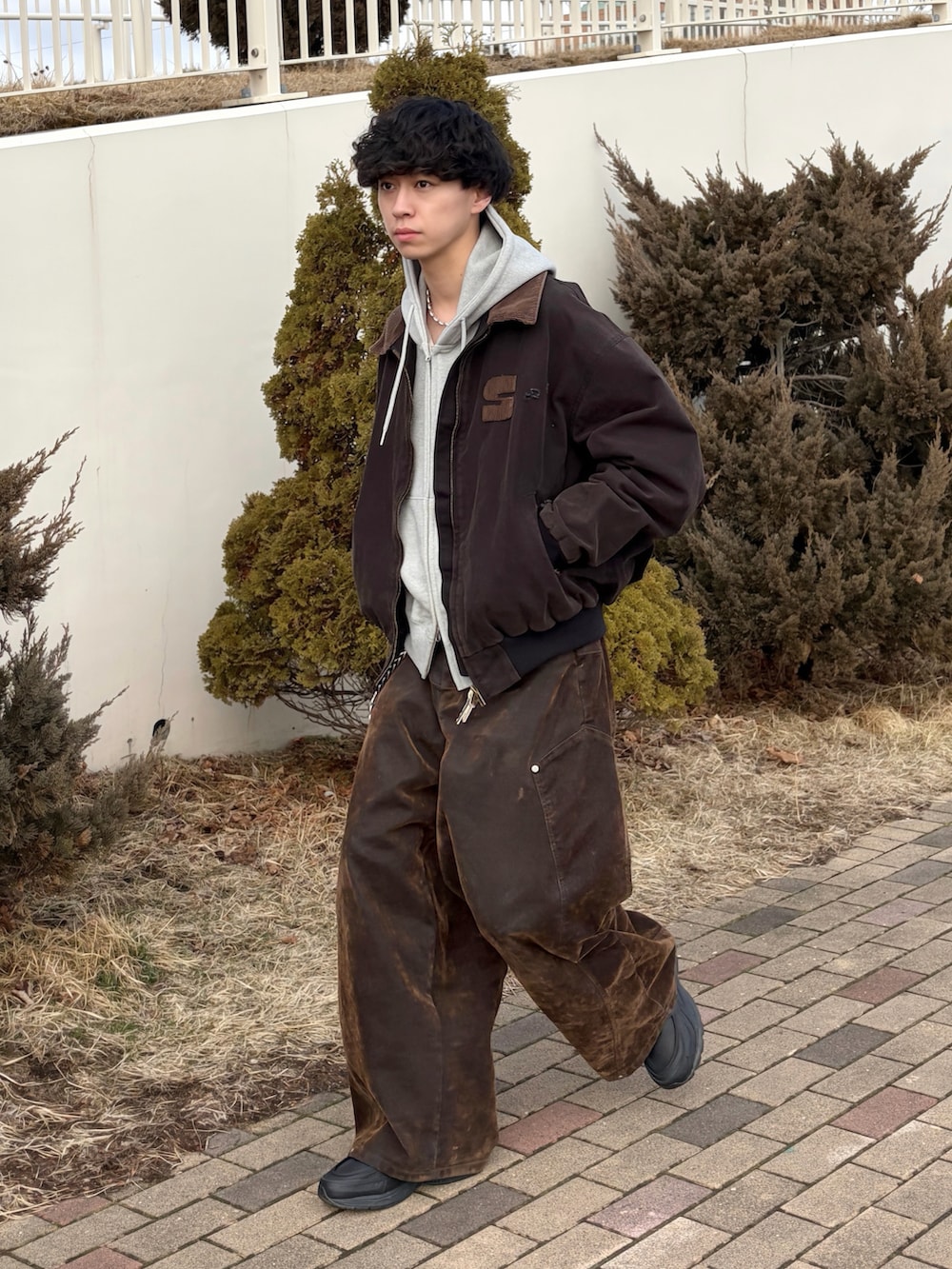 ブラック系のブルゾン、グレー系のパーカー、ブラウン系のデニムパンツを着用したメンズの春コーディネートの4枚目の写真