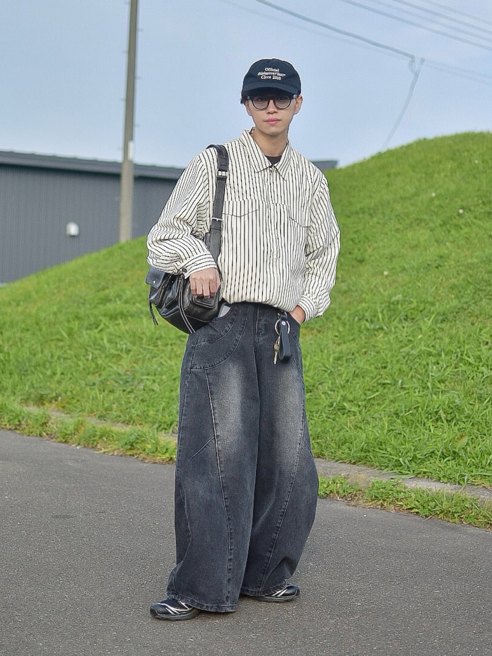 ホワイト系のブルゾン、ブラック系のデニムパンツ、ブラック系のショルダーバッグを着用したメンズの秋コーディネートの3枚目の写真