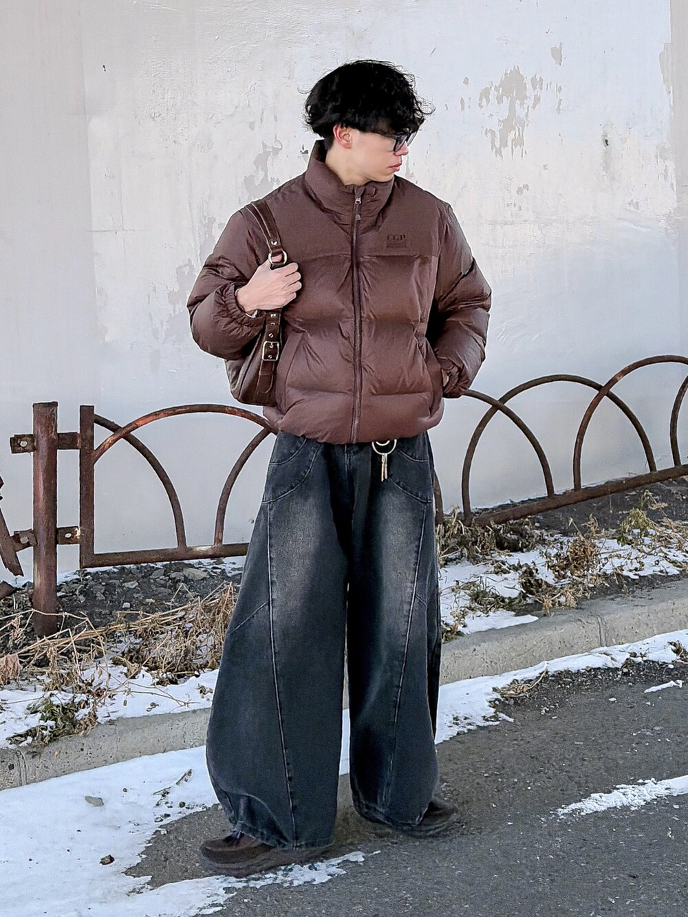 ブラウン系のダウンジャケット/コート、ブラック系のニット/セーター、ブラック系のデニムパンツを着用したメンズの冬コーディネートの2枚目の写真