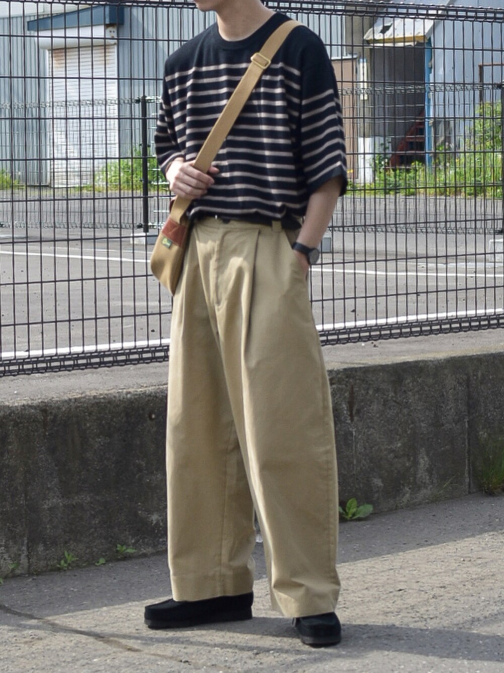 ブラック系のニット/セーター、ベージュ系のその他パンツ、ブラック系のモカシン/デッキシューズを着用したメンズの夏コーディネートの2枚目の写真
