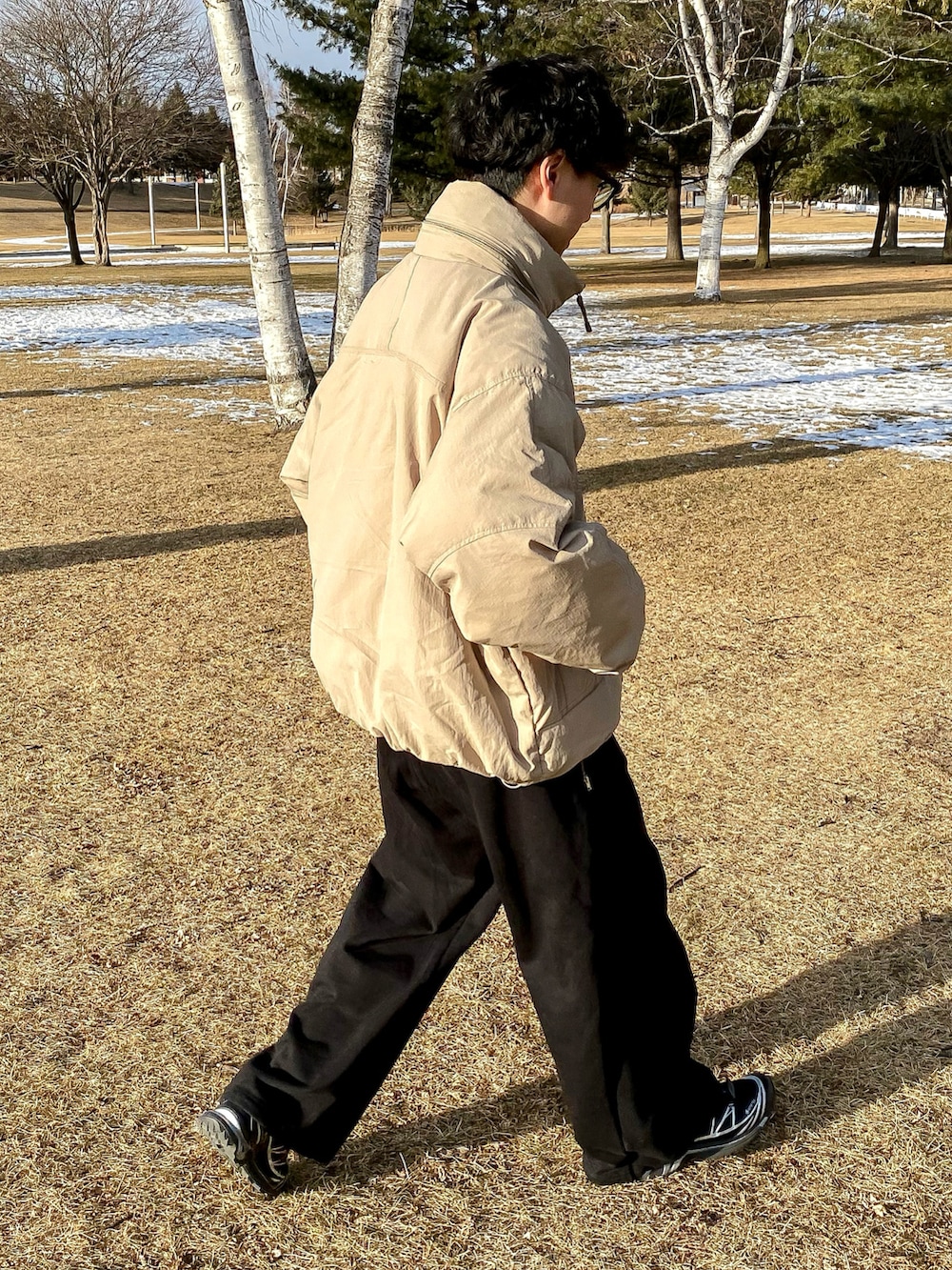 グリーン系のダウンジャケット/コート、ブラック系のスウェットパンツ、ブラック系のスニーカーを着用したメンズの冬コーディネートの4枚目の写真