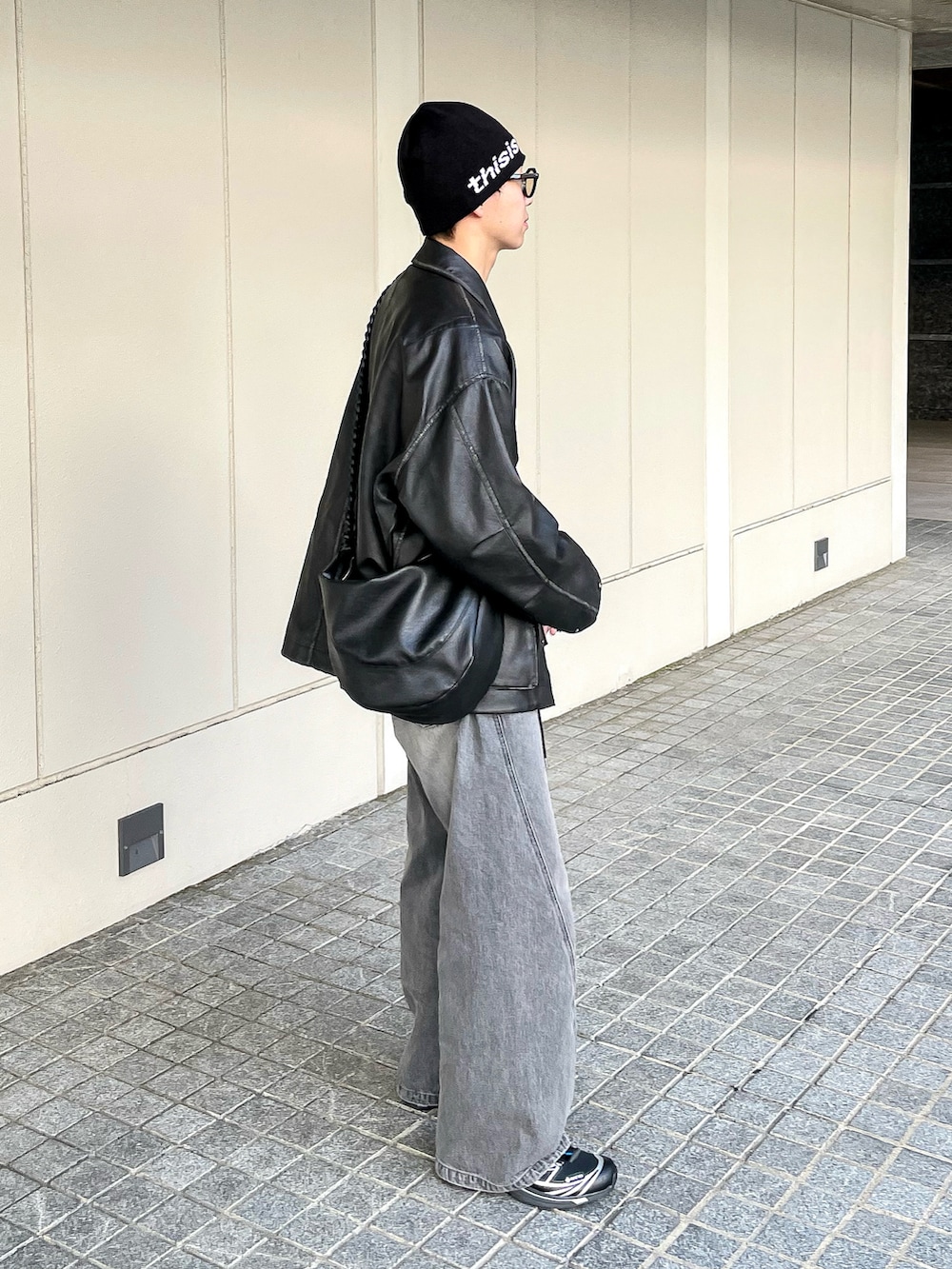 ブラック系のブルゾン、グレー系のニット/セーター、グレー系のデニムパンツを着用したメンズの冬コーディネートの4枚目の写真