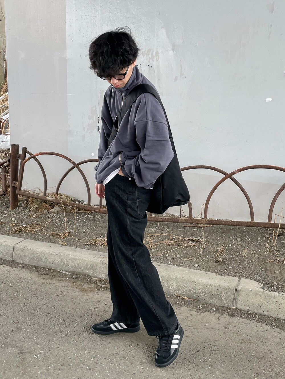 グレー系のスウェット、ブラック系のデニムパンツ、ブラック系のショルダーバッグを着用したメンズの冬コーディネートの4枚目の写真