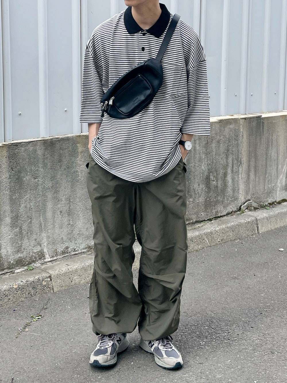 ブラック系のポロシャツ、ブラック系のボディバッグ/ウエストポーチ、グレー系のスニーカーを着用したメンズの夏コーディネートの5枚目の写真