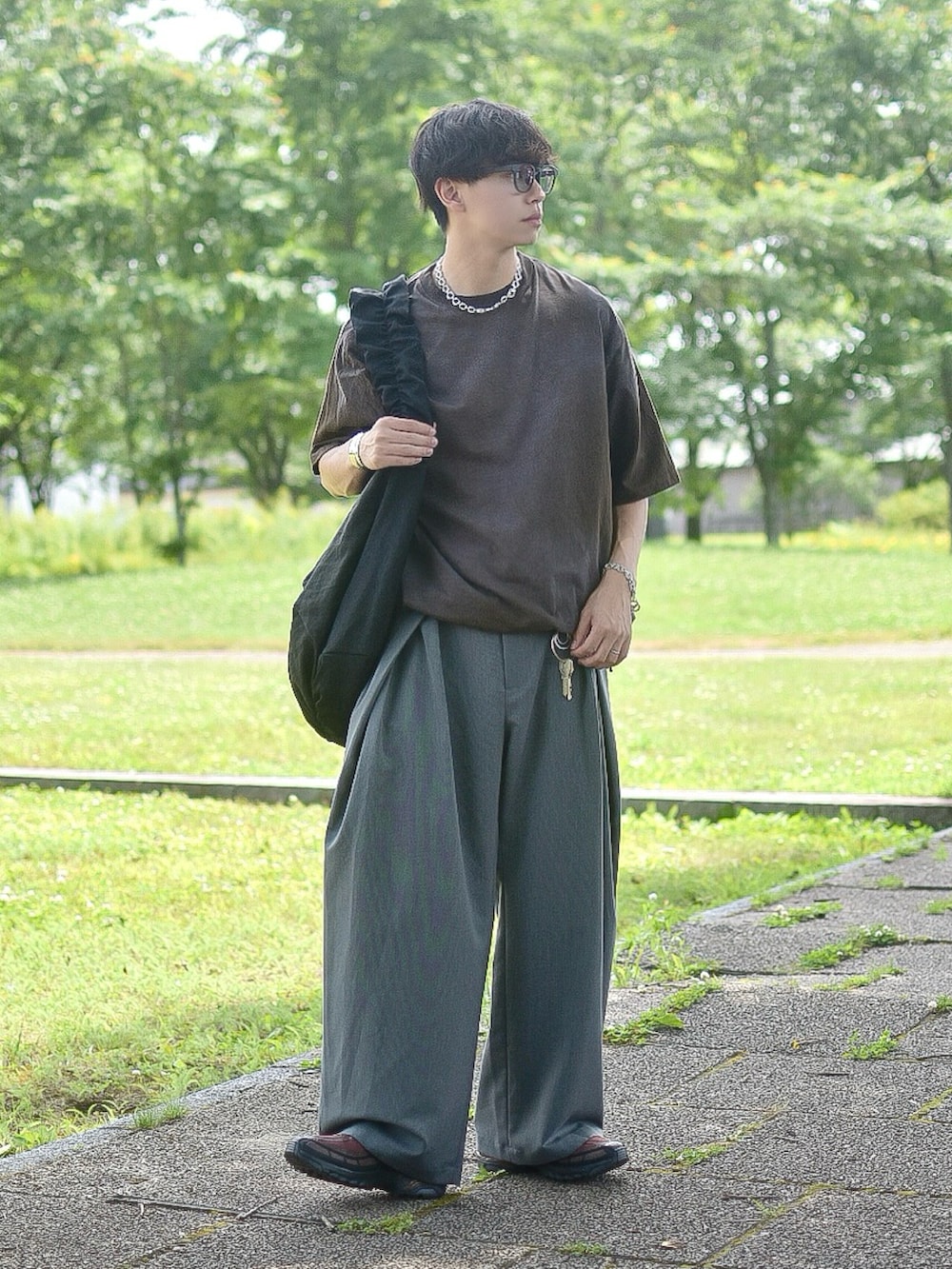 ブラウン系のTシャツ/カットソー、グレー系のスラックス、ブラウン系のスニーカーを着用したメンズの夏コーディネートの3枚目の写真