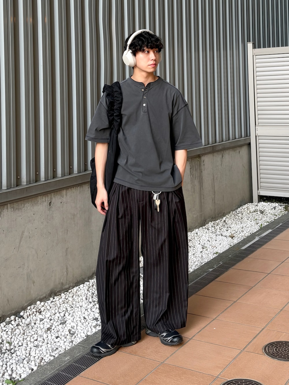 ブラック系のTシャツ/カットソー、ブラック系のスラックス、ブラック系のショルダーバッグを着用したメンズの夏コーディネートの2枚目の写真