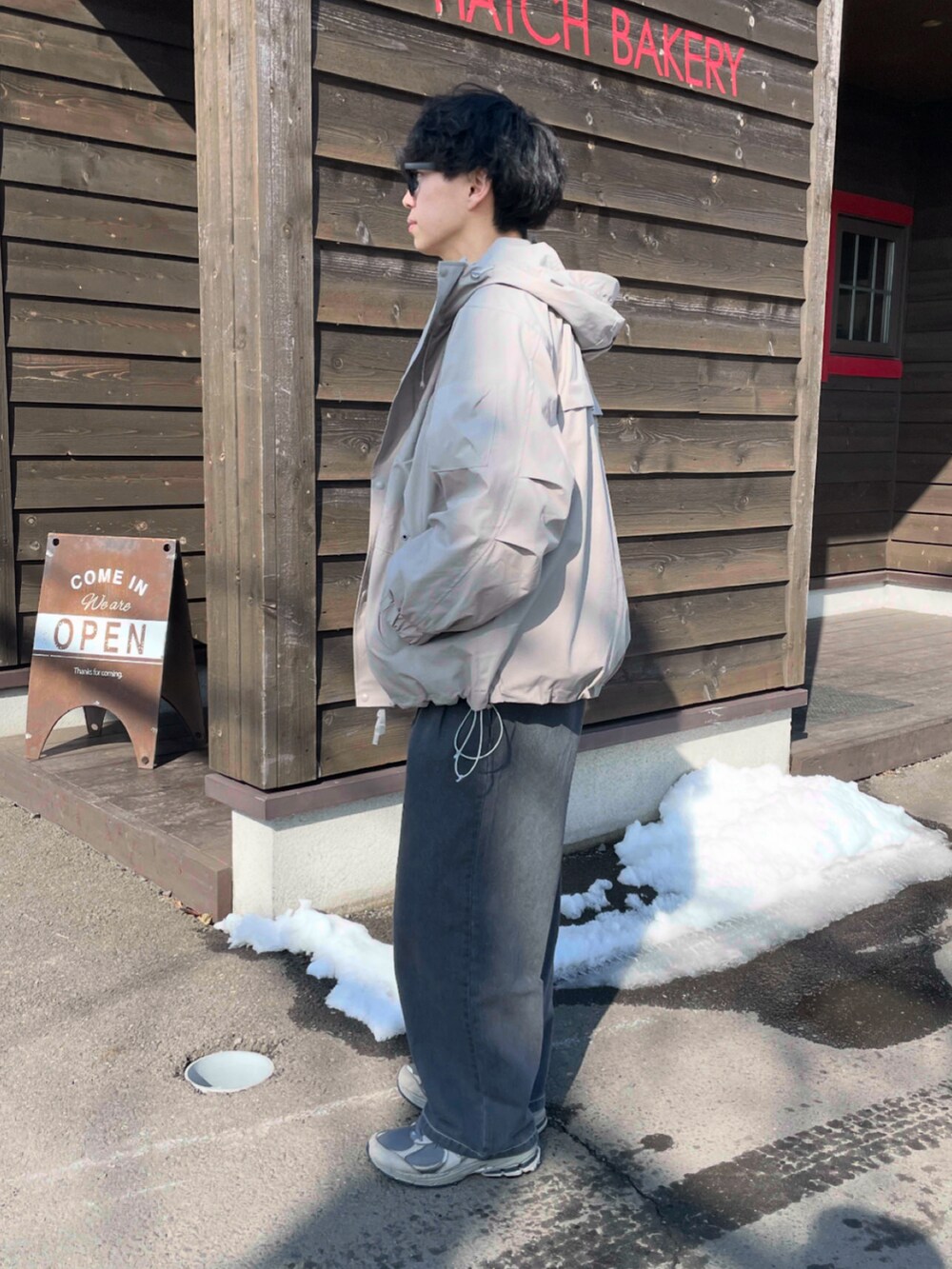 ベージュ系のマウンテンパーカー、グレー系のデニムパンツ、グレー系のスニーカーを着用したメンズの春コーディネートの3枚目の写真