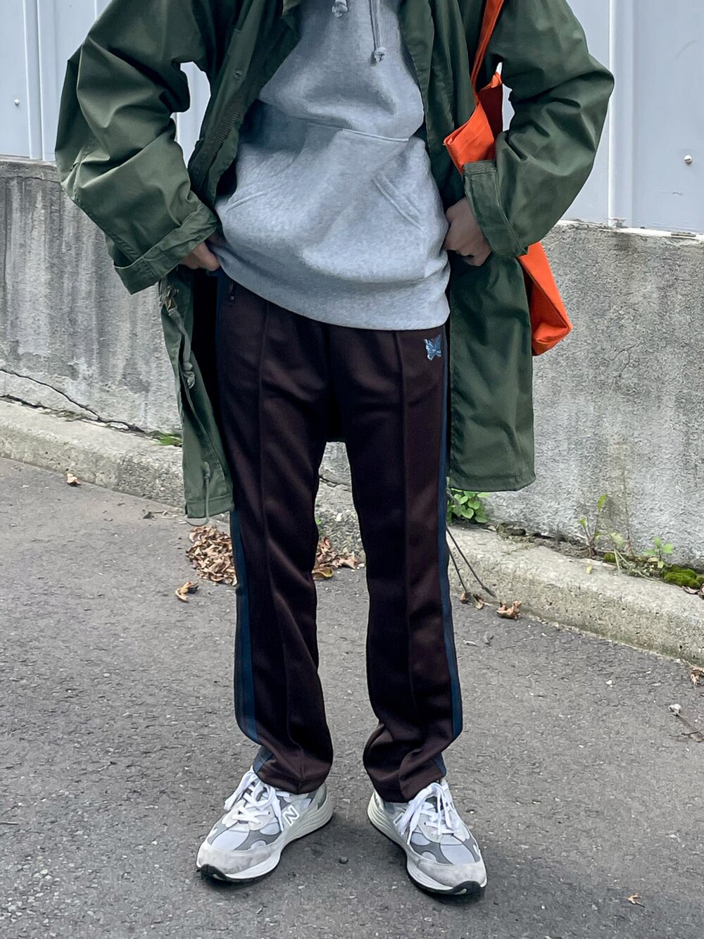 ブラウン系のパンツ、オレンジ系のトートバッグを着用したメンズの秋コーディネートの5枚目の写真