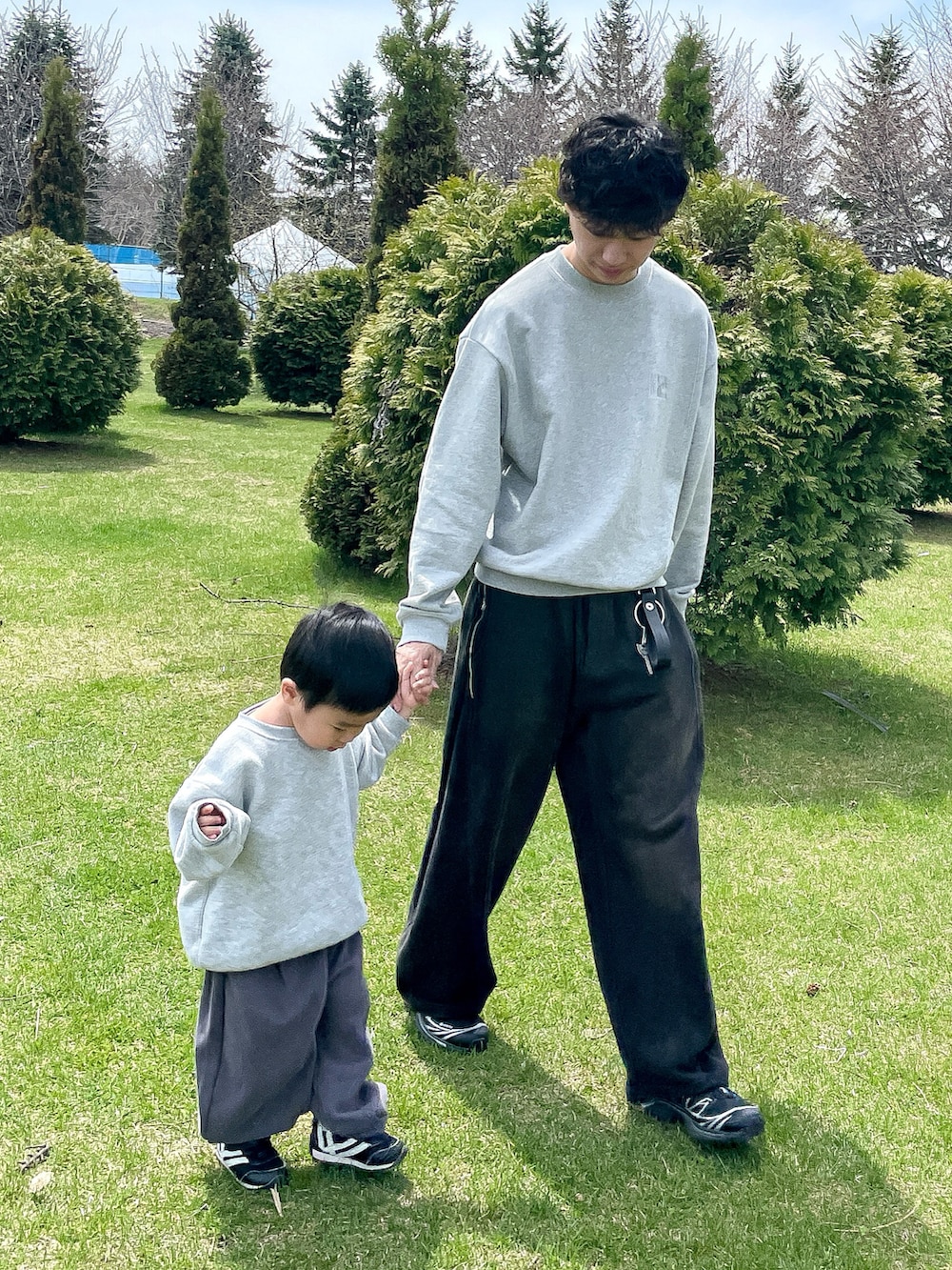 グレー系のスウェット、ブラック系のスウェットパンツ、ブラック系のスニーカーを着用したメンズの春コーディネートの2枚目の写真