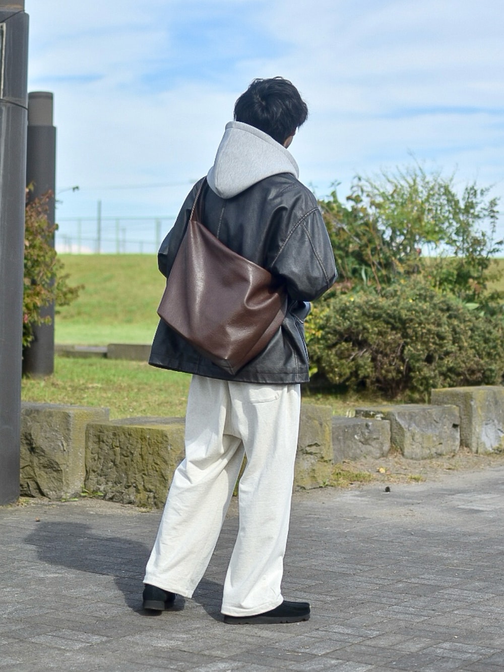 ブラック系のブルゾン、グレー系のパーカー、ホワイト系のスウェットパンツを着用したメンズの秋コーディネートの5枚目の写真