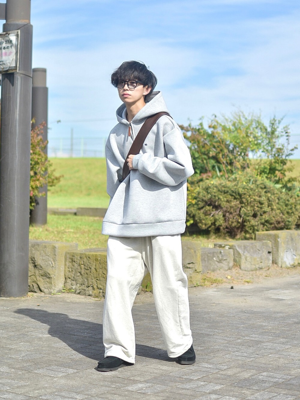ブラック系のブルゾン、グレー系のパーカー、ホワイト系のスウェットパンツを着用したメンズの秋コーディネートの4枚目の写真