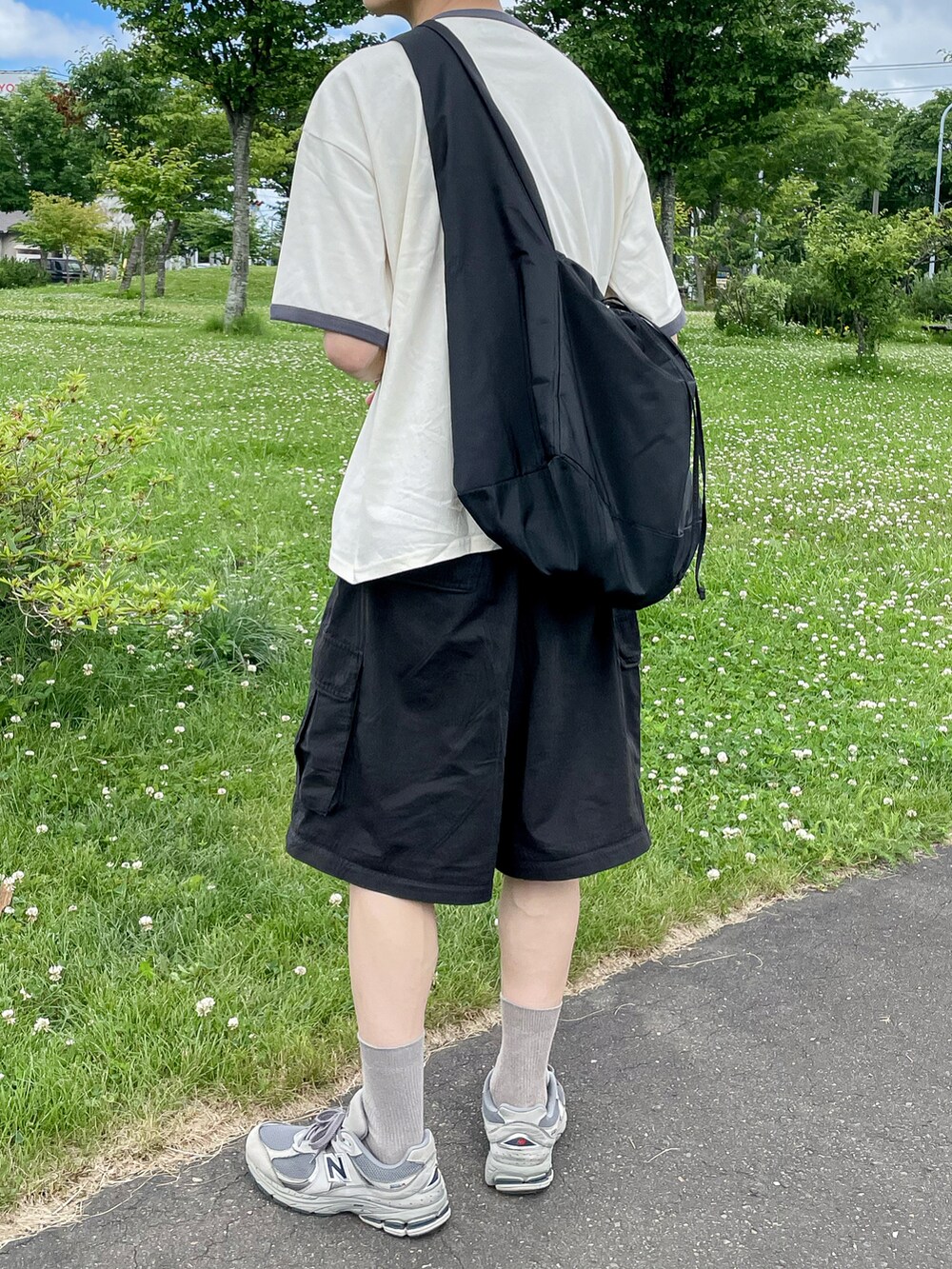 ホワイト系のトップス、ブラック系のパンツ、グレー系のスニーカーを着用したメンズの夏コーディネートの4枚目の写真