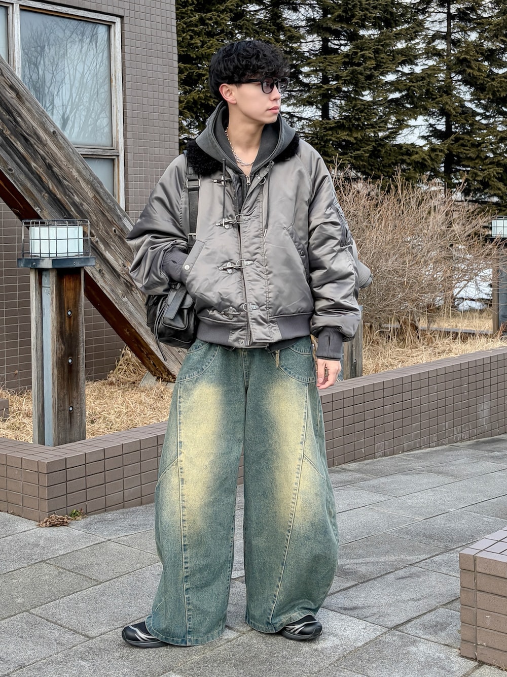 グレー系のパーカー、グレー系のブルゾン、ブルー系のデニムパンツを着用したメンズの冬コーディネートの3枚目の写真