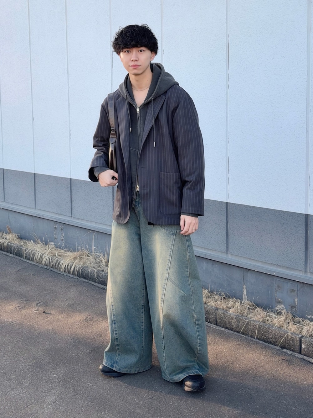 グレー系のテーラードジャケット、グレー系のパーカー、ブルー系のデニムパンツを着用したメンズの冬コーディネートの2枚目の写真