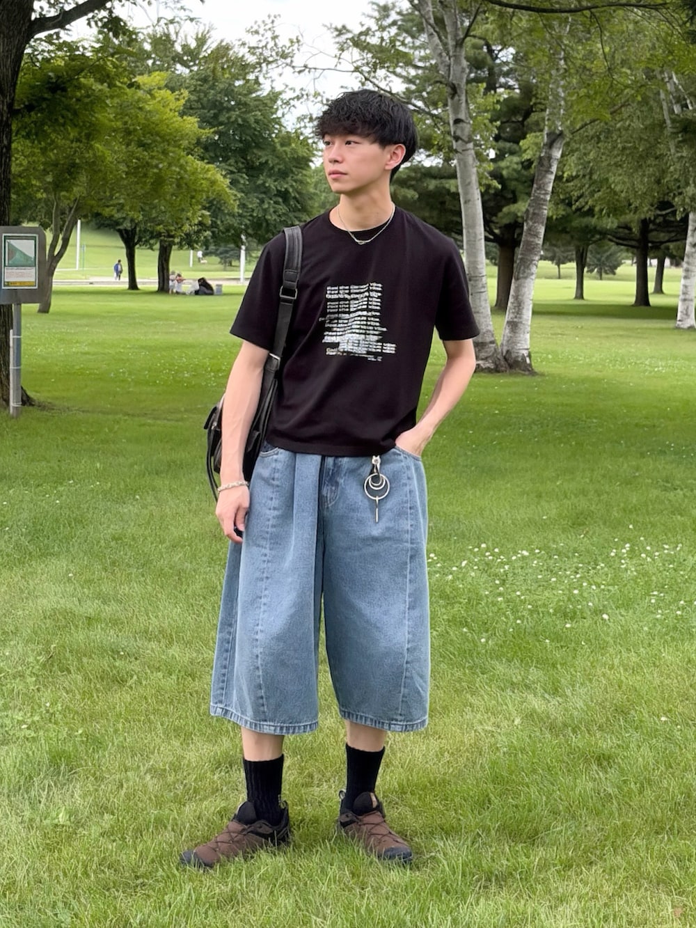 ブラウン系のスニーカー、ブルー系のデニムパンツ、ブラック系のTシャツ/カットソーを着用したメンズの夏コーディネートの2枚目の写真