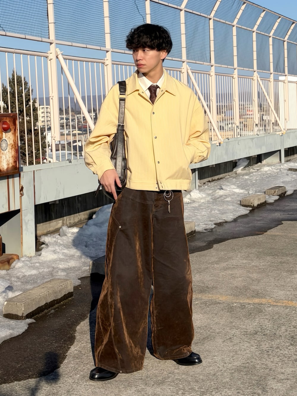 イエロー系のブルゾン、ホワイト系のシャツ/ブラウス、ブラウン系のデニムパンツを着用したメンズの冬コーディネートの2枚目の写真