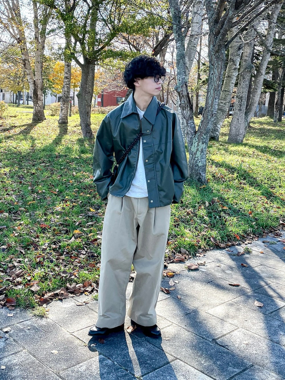 グリーン系のブルゾン、ベージュ系のスウェット、ブラック系のローファーを着用したメンズの秋コーディネートの2枚目の写真