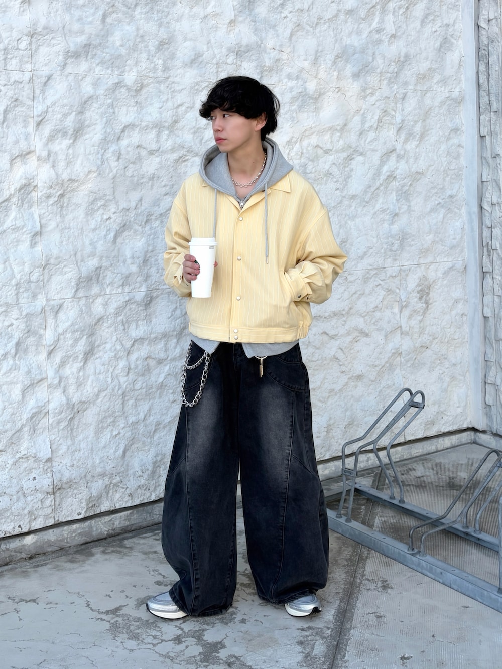 イエロー系のブルゾン、グレー系のパーカー、ブラック系のデニムパンツを着用したメンズの春コーディネートの3枚目の写真