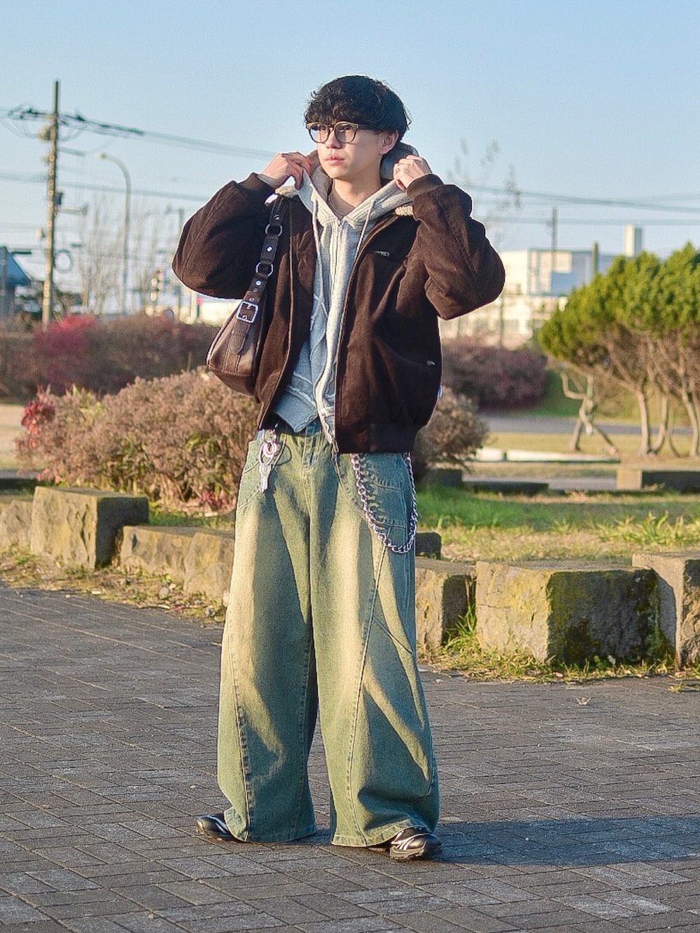 ブラウン系のブルゾン、ブルー系のデニムパンツ、グレー系のパーカーを着用したメンズの秋コーディネートの2枚目の写真