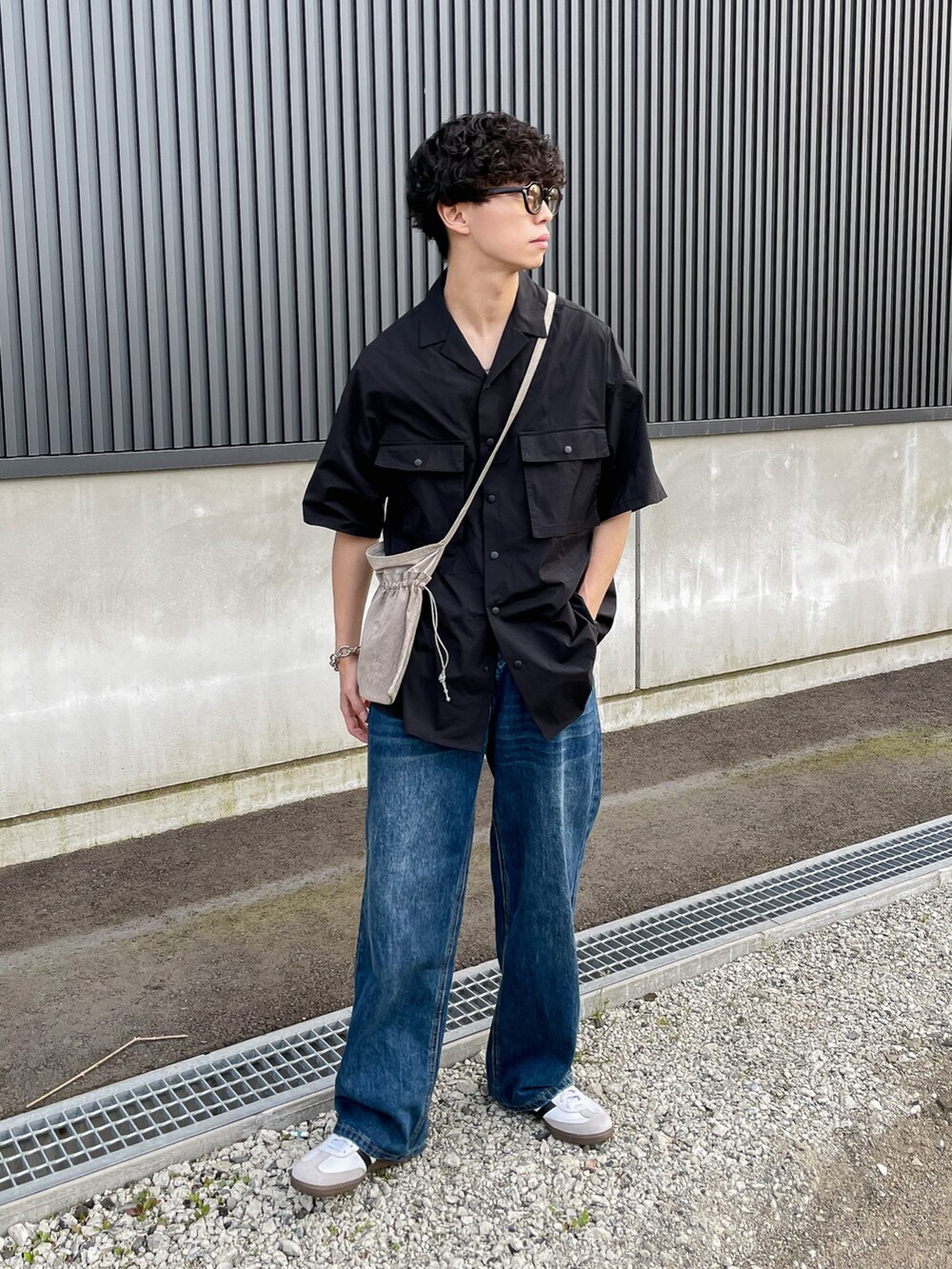 ブラック系のシャツ/ブラウス、ブルー系のデニムパンツ、ホワイト系のスニーカーを着用したメンズの夏コーディネートの3枚目の写真