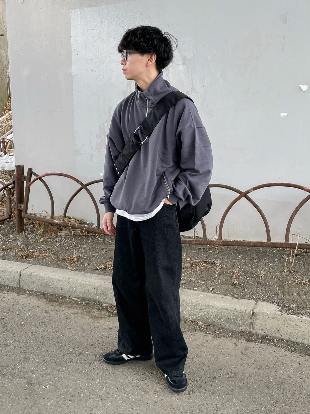 グレー系のスウェット、ブラック系のデニムパンツ、ブラック系のショルダーバッグを着用したメンズの冬コーディネートの2枚目の写真