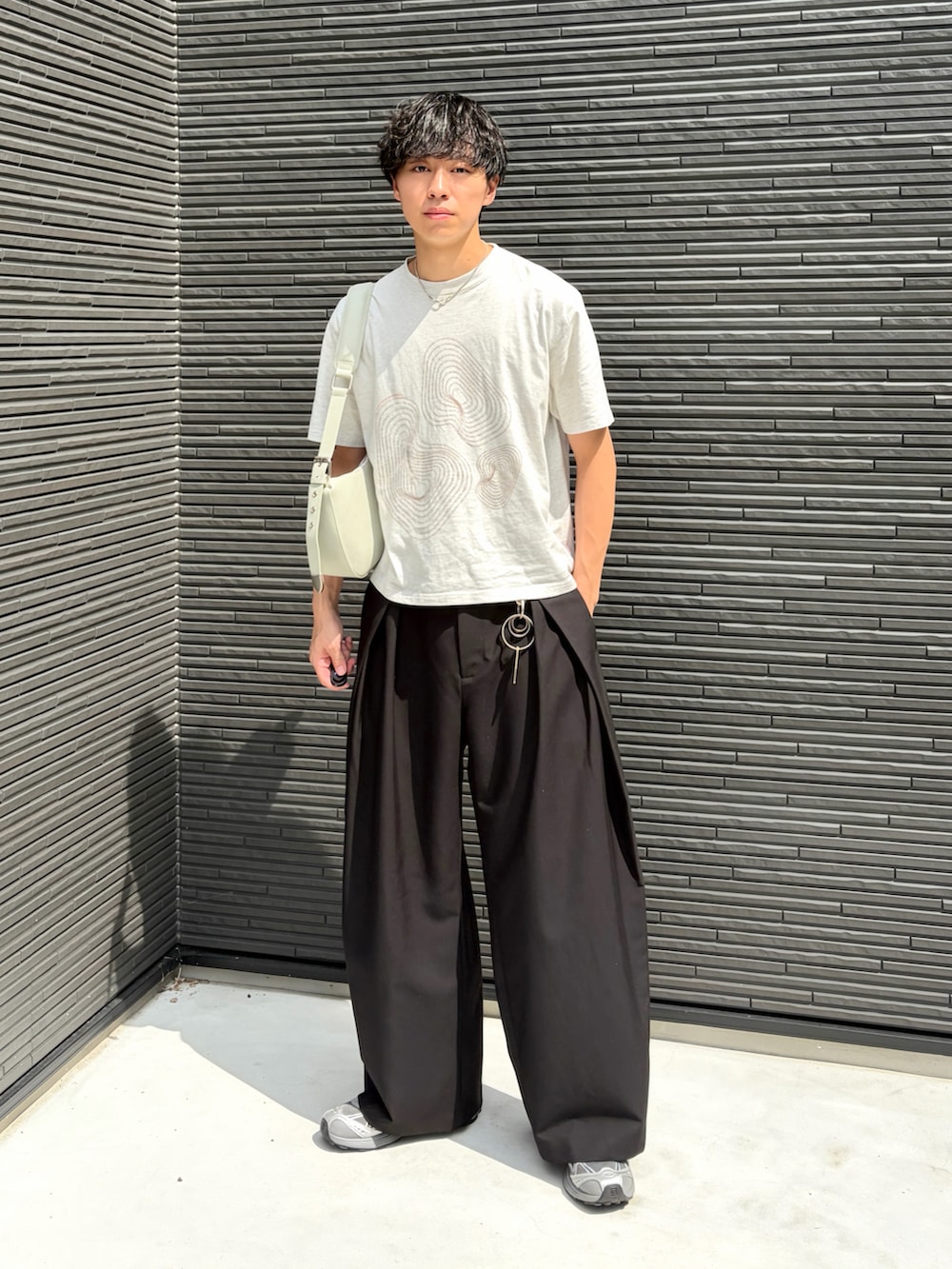 ホワイト系のTシャツ/カットソー、ブラック系のスラックス、グレー系のスニーカーを着用したメンズの夏コーディネートの2枚目の写真