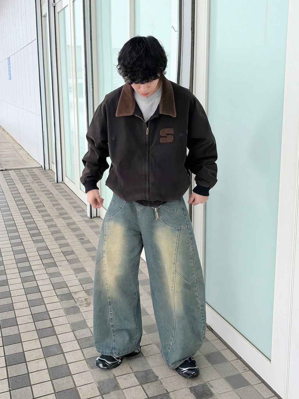 ブラック系のブルゾン、ブルー系のデニムパンツ、ブラック系のスニーカーを着用したメンズの春コーディネートの2枚目の写真