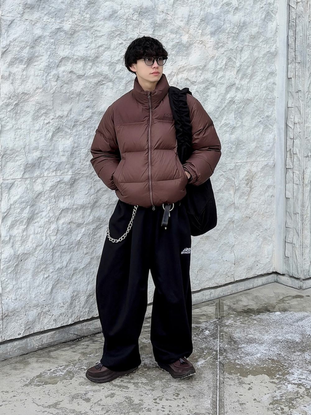 ブラック系のスウェットパンツ、ブラウン系のダウンジャケット/コート、ブラック系のショルダーバッグを着用したメンズの冬コーディネートの2枚目の写真