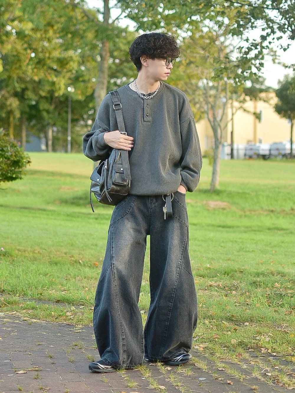 ブラック系のデニムパンツ、グレー系のTシャツ/カットソー、ブラック系のショルダーバッグを着用したメンズの秋コーディネートの3枚目の写真