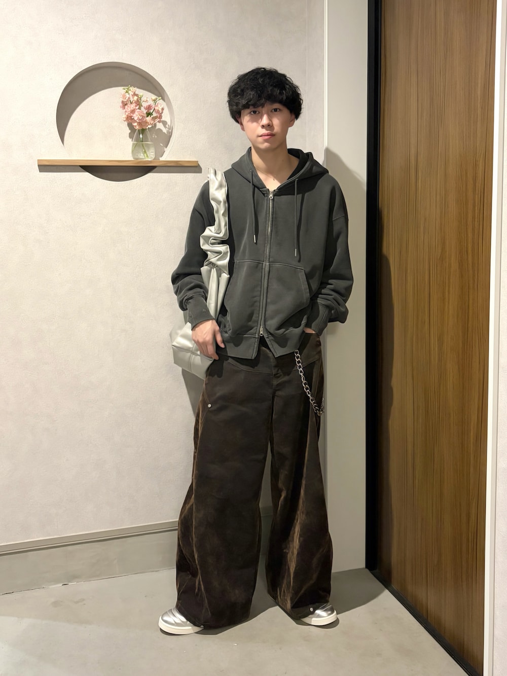 グレー系のパーカー、ブラウン系のデニムパンツ、シルバー系のショルダーバッグを着用したメンズの冬コーディネートの2枚目の写真