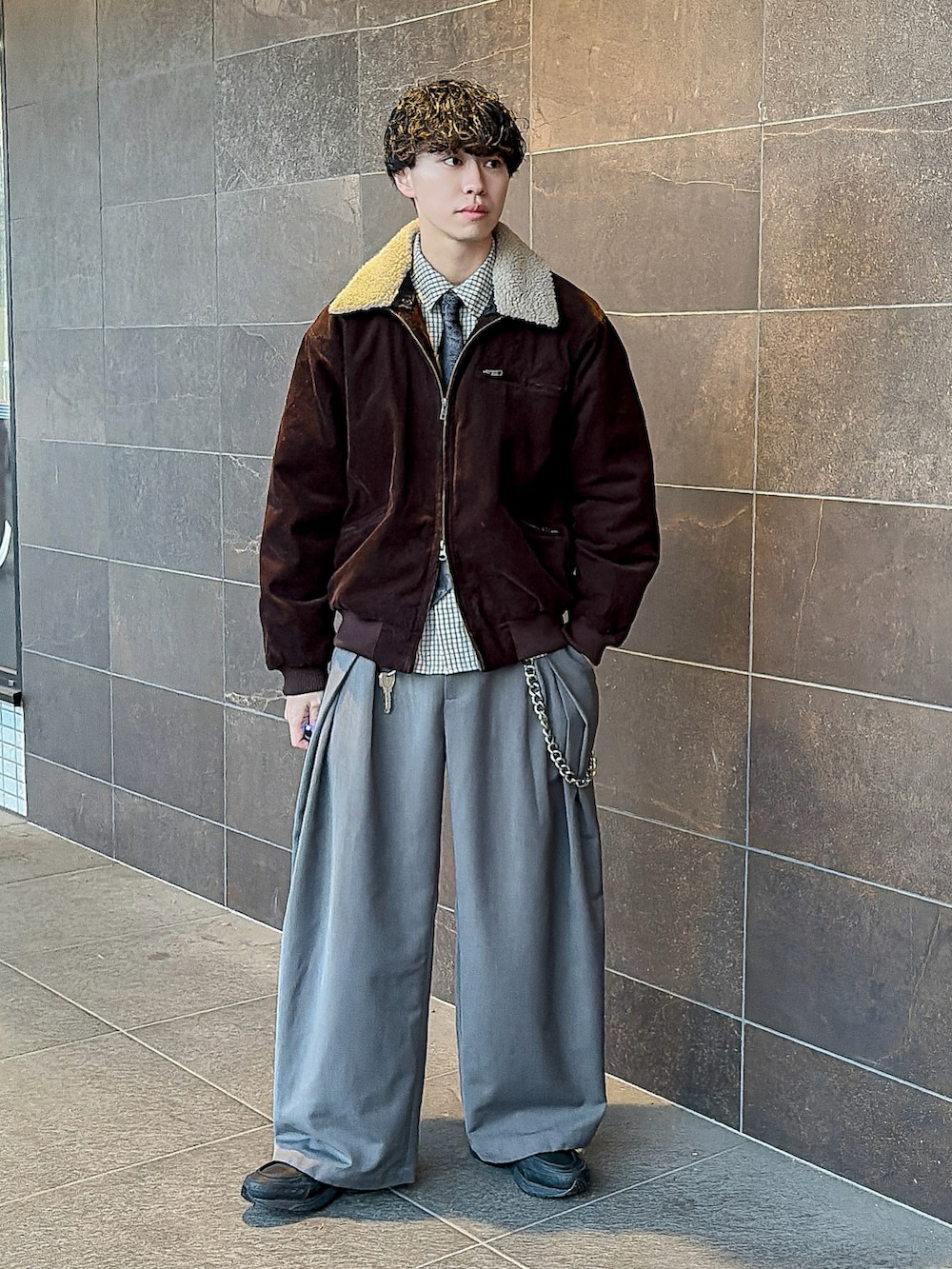 ブラウン系のブルゾン、ブラック系のネクタイ、グレー系のスラックスを着用したメンズの冬コーディネートの3枚目の写真