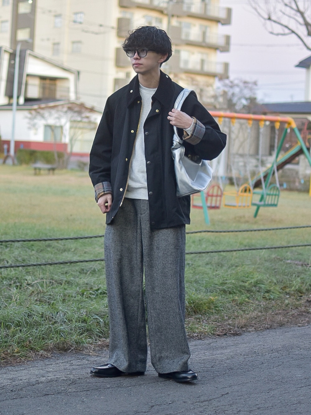 ブラック系のステンカラーコート、ベージュ系のスウェット、グレー系のスラックスを着用したメンズの冬コーディネートの2枚目の写真