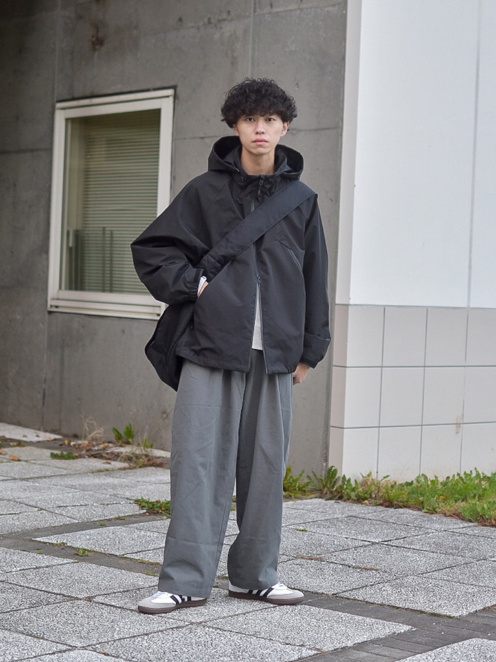 グレー系のデニムパンツ、ブラック系のブルゾン、ベージュ系のスウェットを着用したメンズの秋コーディネートの2枚目の写真
