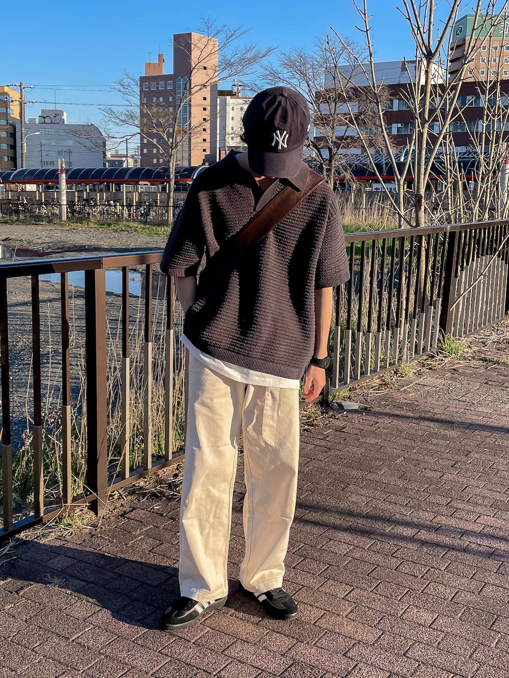 グレー系のポロシャツ、ホワイト系のタンクトップ、ホワイト系のデニムパンツを着用したメンズの春コーディネートの2枚目の写真