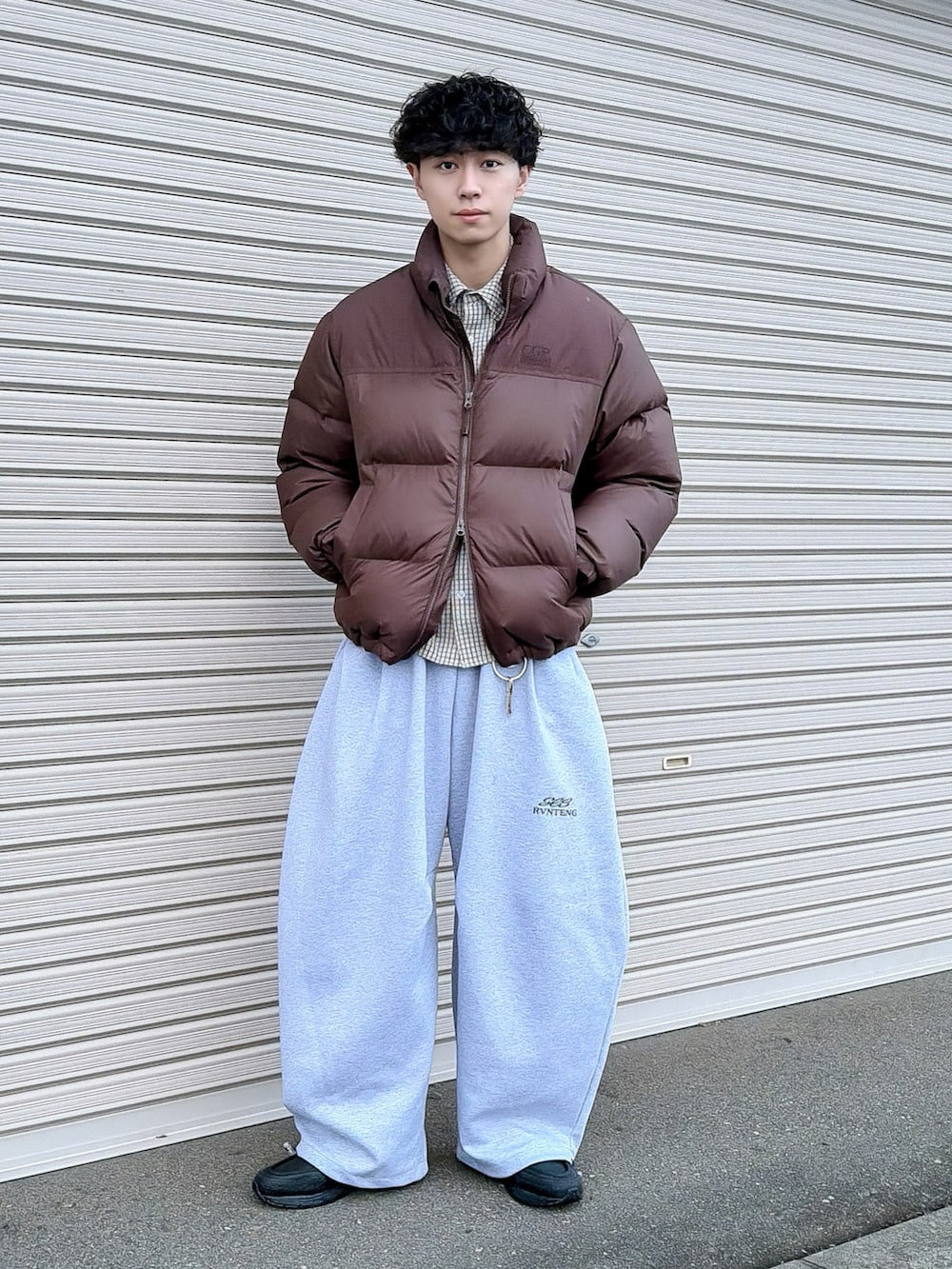 ブラウン系のダウンジャケット/コート、グレー系のスウェットパンツ、ホワイト系のシャツ/ブラウスを着用したメンズの冬コーディネートの2枚目の写真