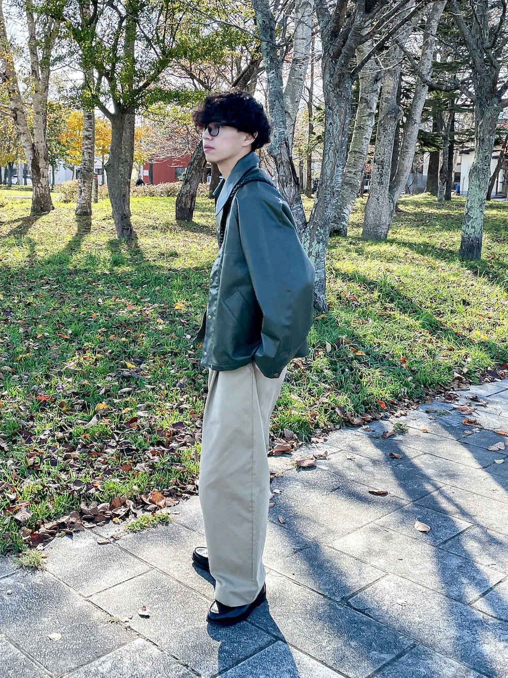 グリーン系のブルゾン、ベージュ系のスウェット、ブラック系のローファーを着用したメンズの秋コーディネートの4枚目の写真