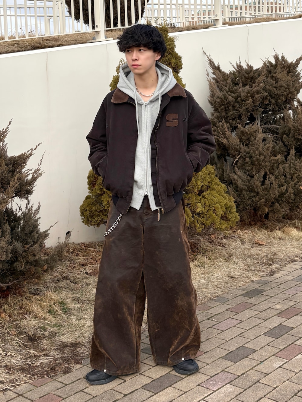 ブラック系のブルゾン、グレー系のパーカー、ブラウン系のデニムパンツを着用したメンズの春コーディネートの3枚目の写真