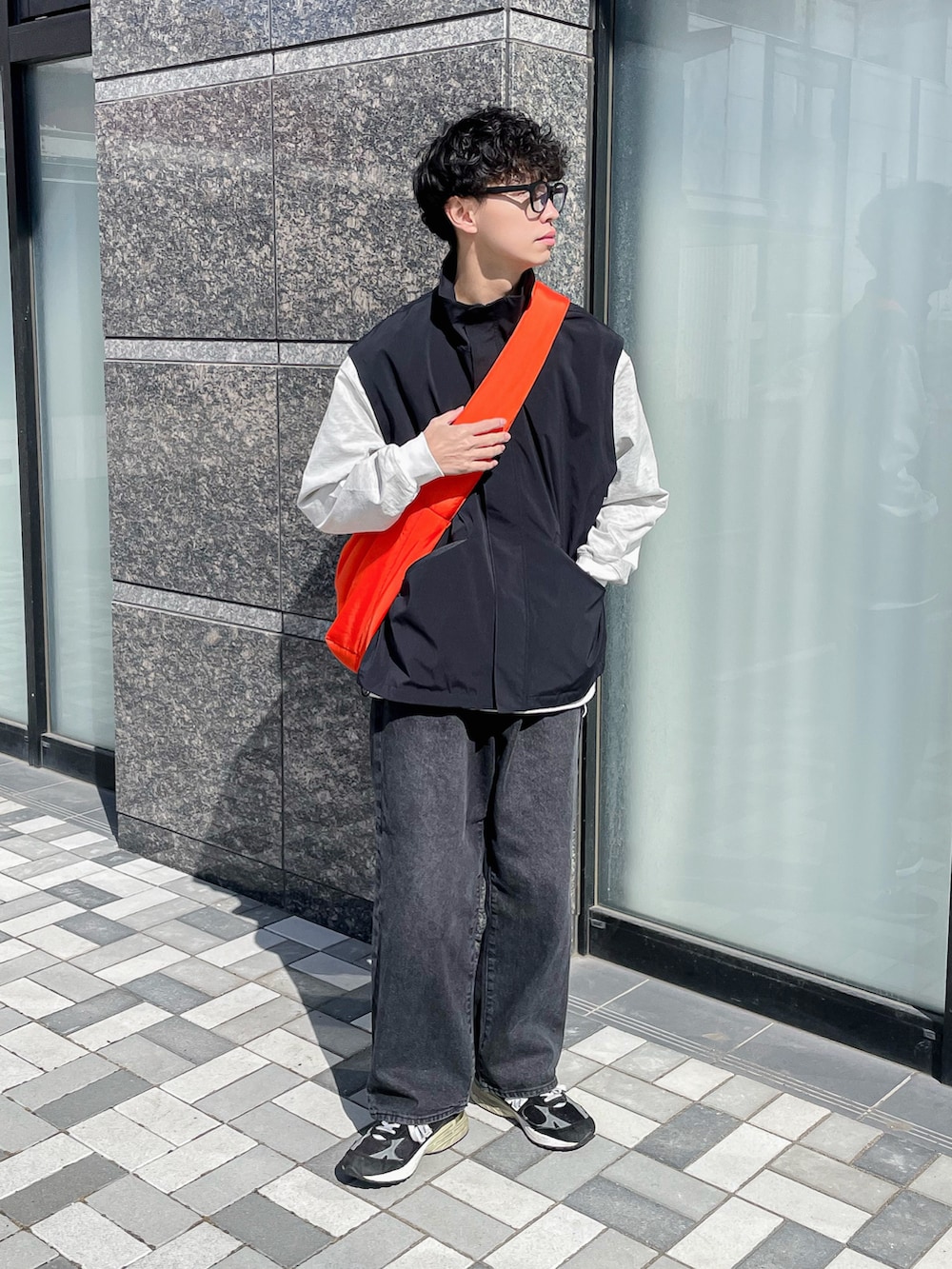 ブラック系のブルゾン、ブラック系のデニムパンツ、オレンジ系のショルダーバッグを着用したメンズの春コーディネートの3枚目の写真