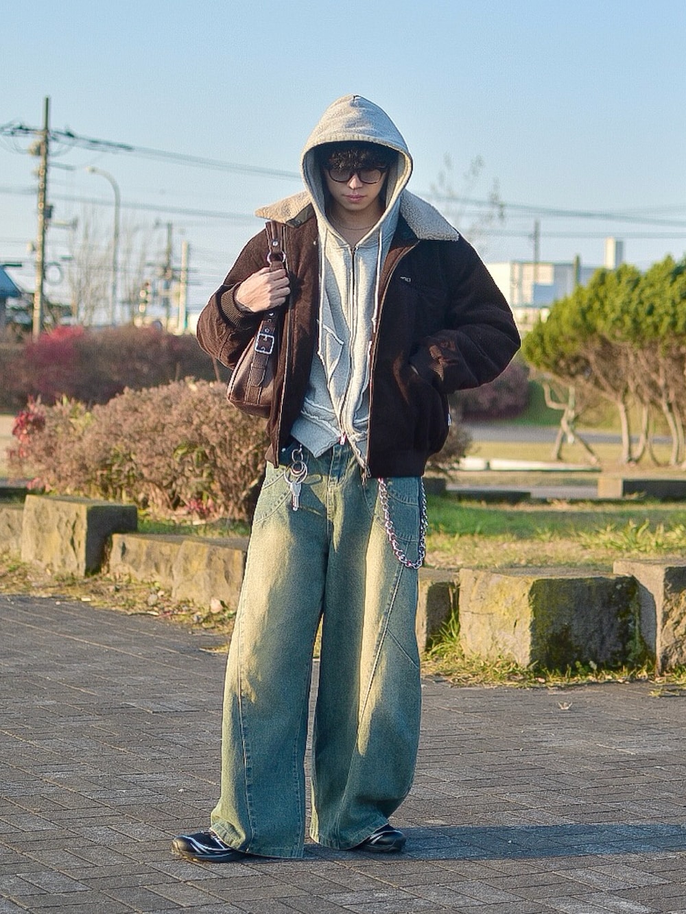 ブラウン系のブルゾン、ブルー系のデニムパンツ、グレー系のパーカーを着用したメンズの秋コーディネートの3枚目の写真