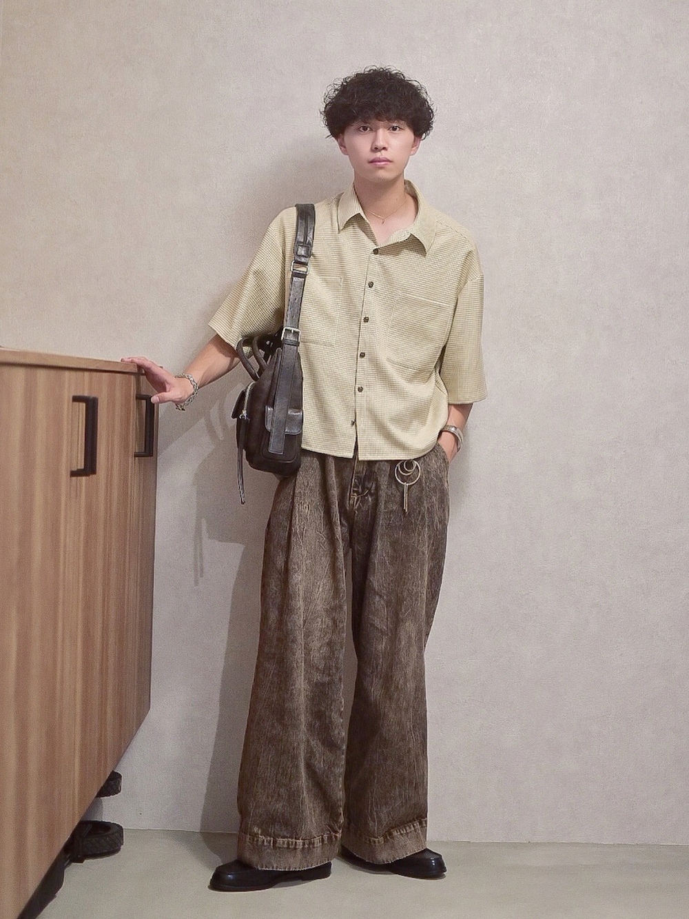 ブラック系のデニムパンツ、ベージュ系のシャツ/ブラウス、ブラック系のショルダーバッグを着用したメンズの秋コーディネートの2枚目の写真