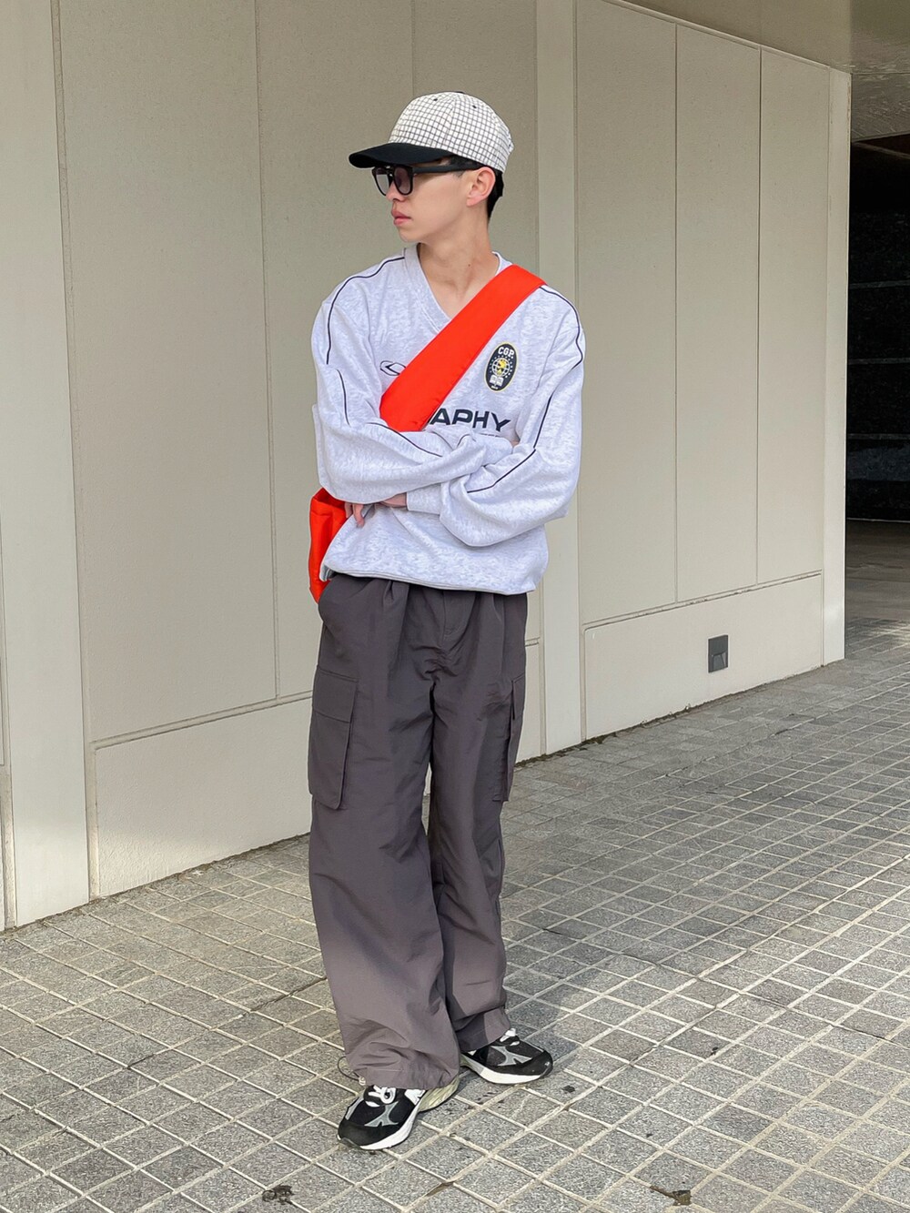 グレー系のスウェット、グレー系のカーゴパンツ、オレンジ系のショルダーバッグを着用したメンズの春コーディネートの2枚目の写真